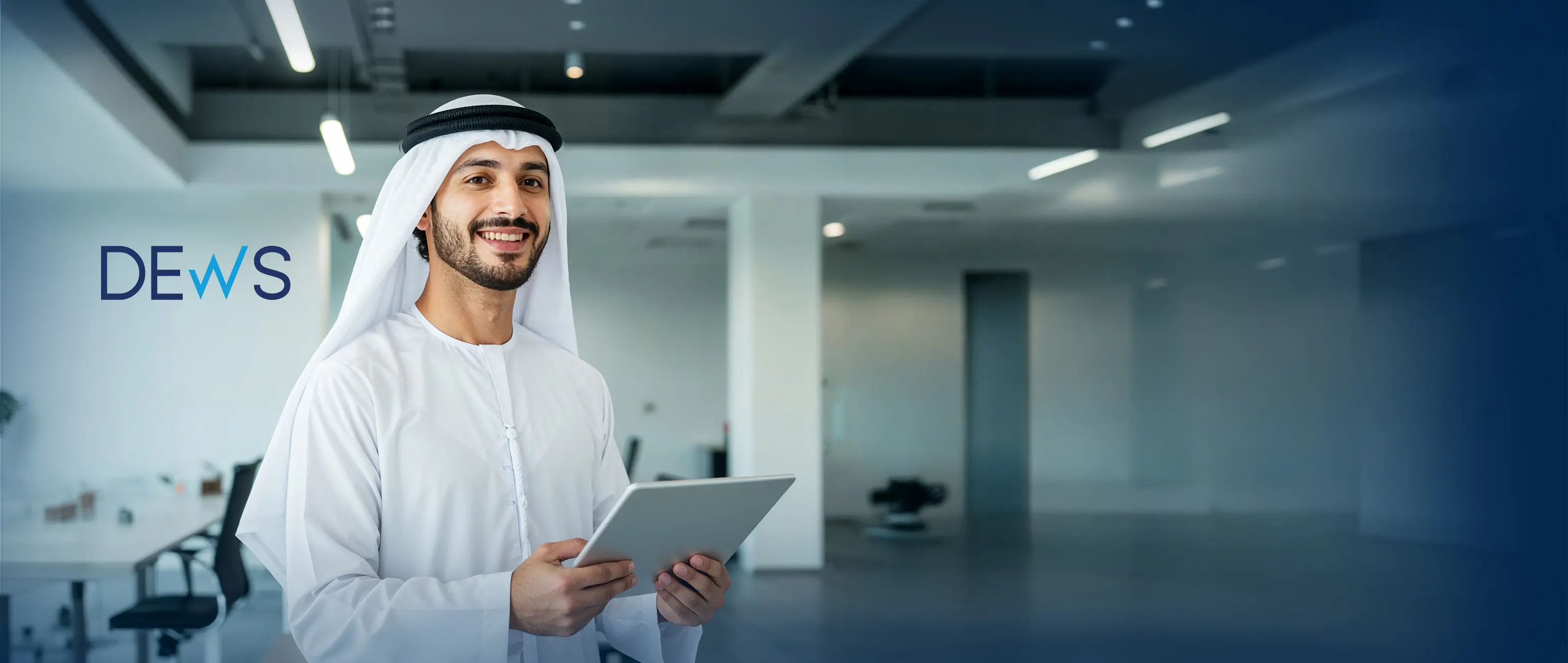 محترف إماراتي مبتسم يحمل جهازاً لوحياً في مكتب شركة حديث، مما يمثل خطة "ديوس" (DEWS) لمدخرات الموظفين في مكان العمل من الصكوك الوطنية.