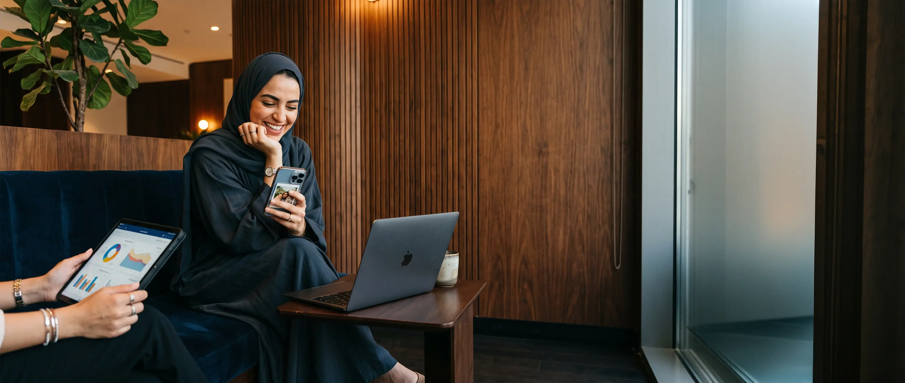 امرأة مبتسمة تستخدم هاتفها الذكي بسعادة بجوار رسوم بيانية مالية رقمية، مما يمثل سهولة وراحة فتح حساب ادخار جديد عبر الإنترنت مع الصكوك الوطنية.