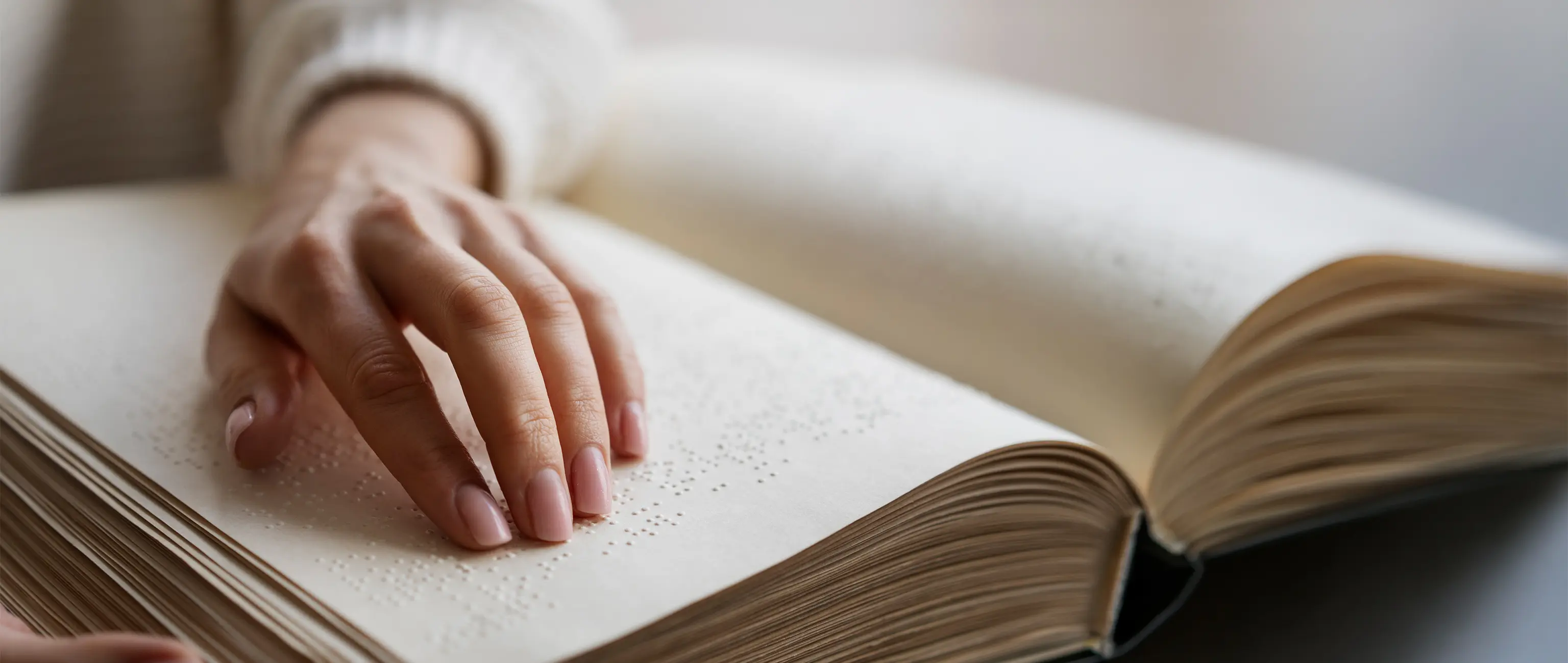 يد تقرأ كتاباً بطريقة برايل، مما يمثل المبادرات الخيرية لدعم المكفوفين وضعاف البصر مع صكوك "وقف النور" من الصكوك الوطنية.